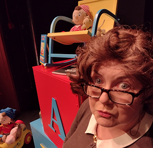 A schoolteacher surrounded by toy Enid Blyton characters